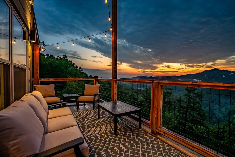 Covered porch seating and mountain sunset beneath string lights