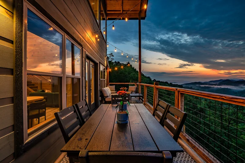Outdoor dining table with potted flowers and sunset mountain view