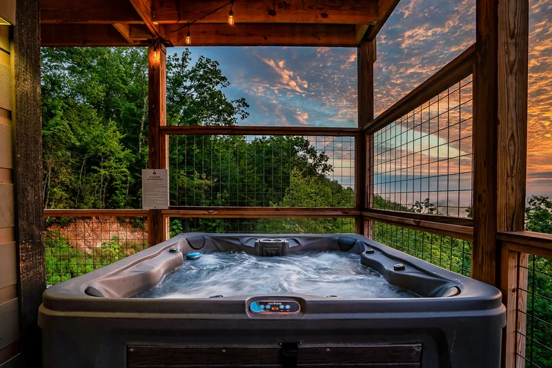 Bubbling hot tub on a screened porch beneath a sunset sky