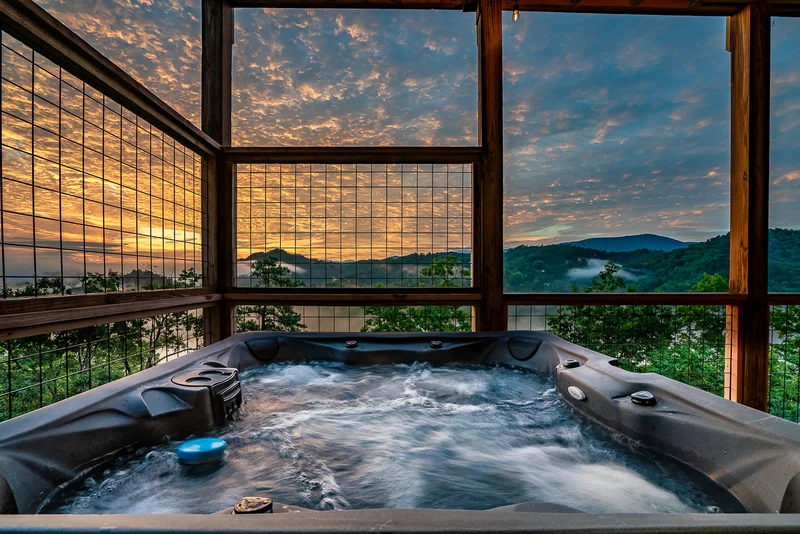 Hot tub on a screened porch with trees and sunset beyond