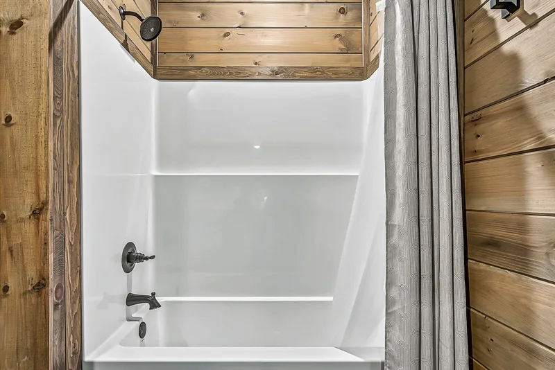 White bathtub with showerhead and patterned curtain