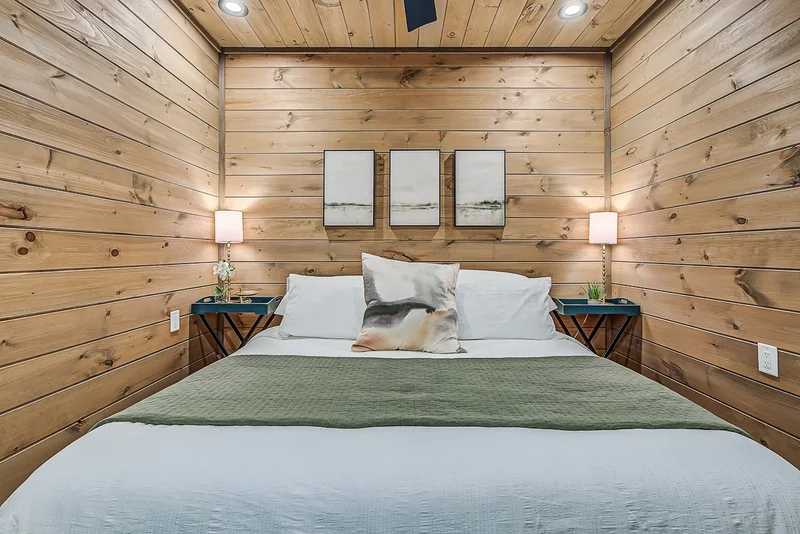 Made bed with green coverlet and three minimalist wall panels