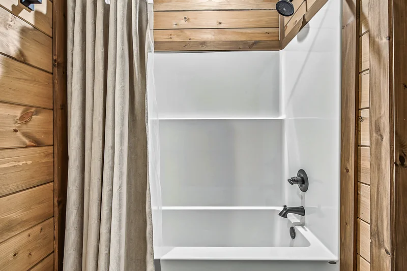 White bathtub with showerhead and patterned curtain