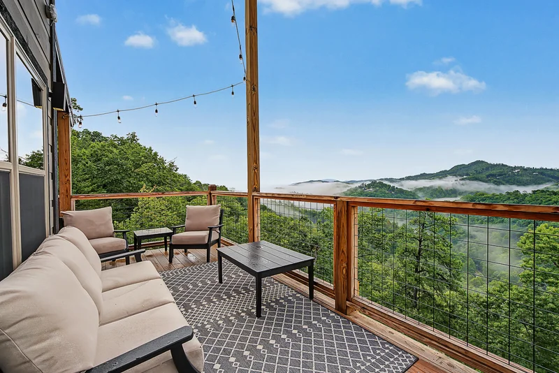 Outdoor sofa and chairs overlooking misty green mountains