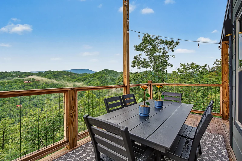 Outdoor dining table with potted flowers and mountain view