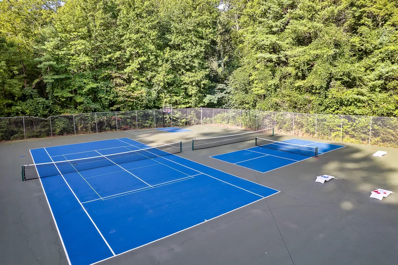 Blue pickleball and basketball courts surrounded by trees